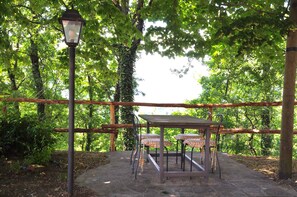 An outdoor seating area with a table and chairs, surrounded by a wooden fence and trees.