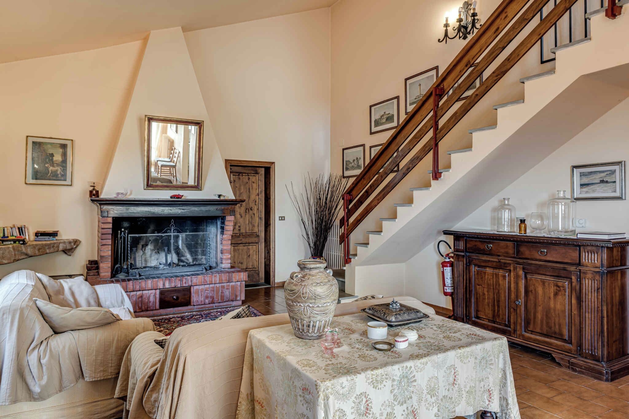 Una sala de estar con chimenea, un sofá, una mesa con adornos y una escalera.