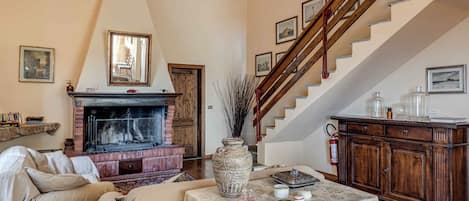A living room with a fireplace, a sofa, a table with decorative items, and a staircase.