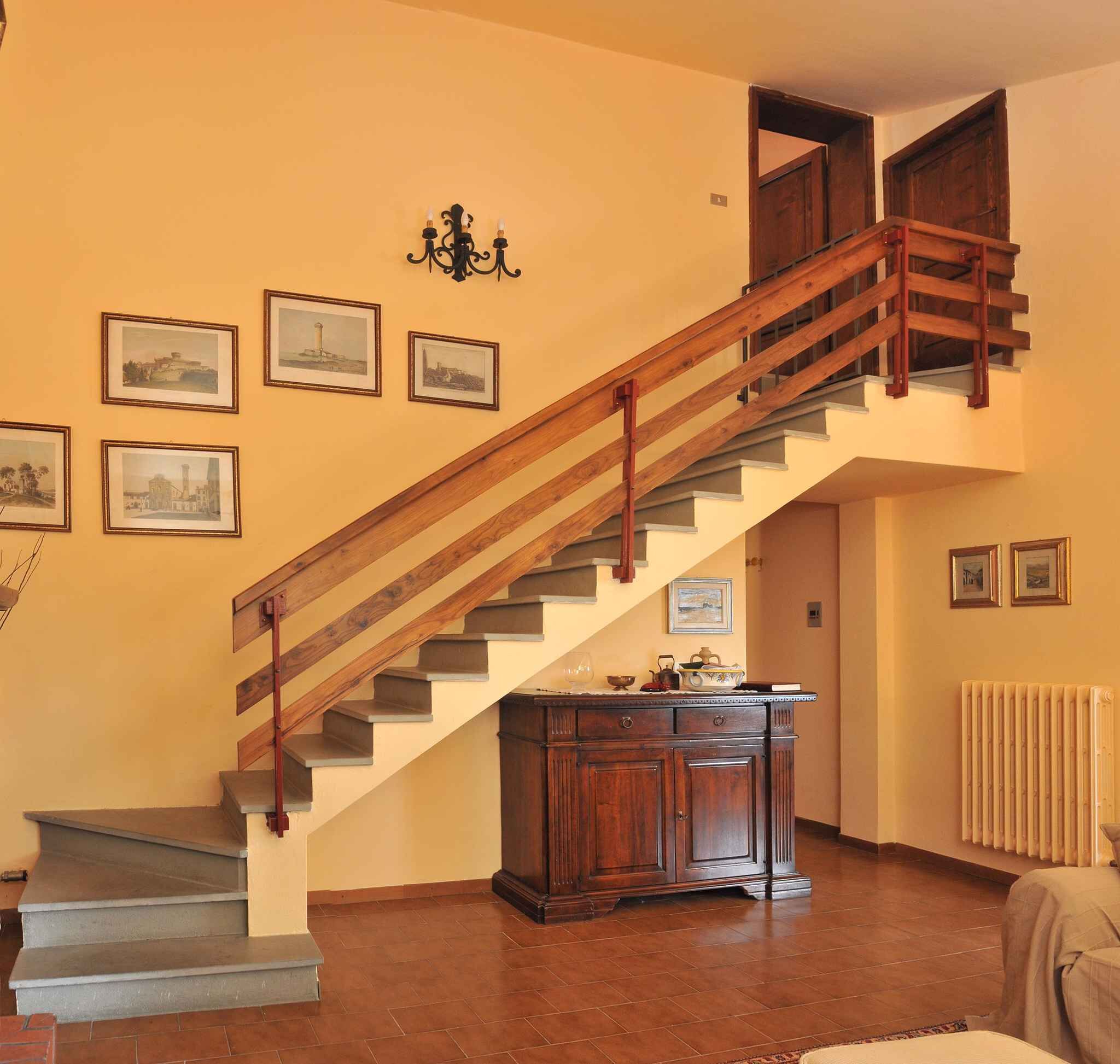 A staircase with wooden railings and a radiator on the wall.