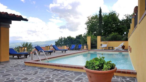 A pool area with lounge chairs and a potted plant. - Holiday apartment mit Pool (Vicchio)