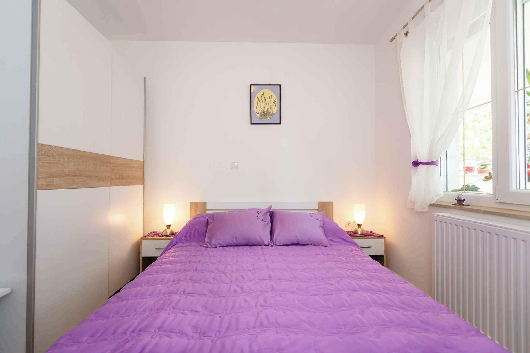 A bedroom with a bed, two bedside tables, a nightstand, a window with curtains, and a wall-mounted picture.