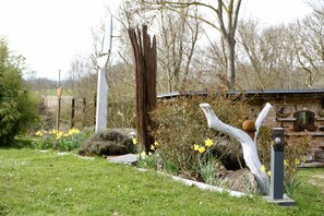 A garden with a white sculpture, a wooden structure, and yellow flowers. - Flotsam - Kunsthof Salsitz (Lohme auf Rügen)