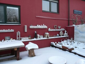 A red building with multiple windows, outdoor seating, and various sculptures and decorations. - Flotsam - Kunsthof Salsitz (Lohme auf Rügen)