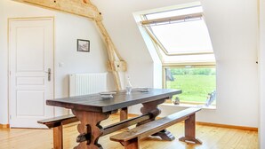 A room with a sloped ceiling, a wooden table with benches, a white radiator, and a window with a view of greenery. - 2 bedroom amazing apartment in Ponts (Ponts)
