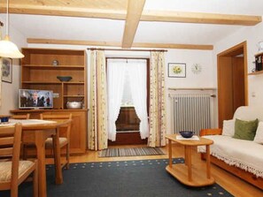 Una sala de estar acogedora con una mesa de comedor de madera, un sofá, un televisor y una estantería.