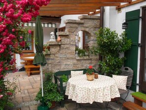 Un patio con una mesa redonda y sillas, un muro de piedra y una puerta verde.