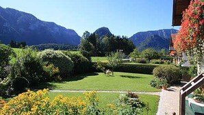 Une vue sur un paysage montagneux, avec un jardin bien entretenu et un bâtiment doté d’un balcon.