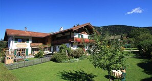 Un bâtiment à deux étages, doté d’un toit en pente, d’une terrasse en bois et d’une cour clôturée.