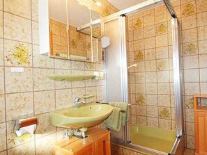 Ein Badezimmer mit Waschbecken, Spiegel, Dusche und gefliesten Wänden.