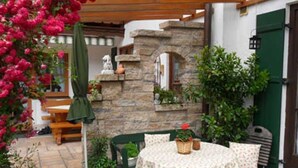 Une terrasse avec une table ronde et des chaises, un mur en pierre et une porte verte.