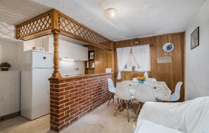 A compact kitchen with a brick accent wall, a wooden bar, and a dining area with a table and chairs. - 2 bedroom gorgeous home in Baska (Baska)