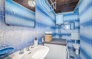 A bathroom with blue textured tiles, a white sink, a towel rack, and a toilet. - 2 bedroom gorgeous home in Baska (Baska)