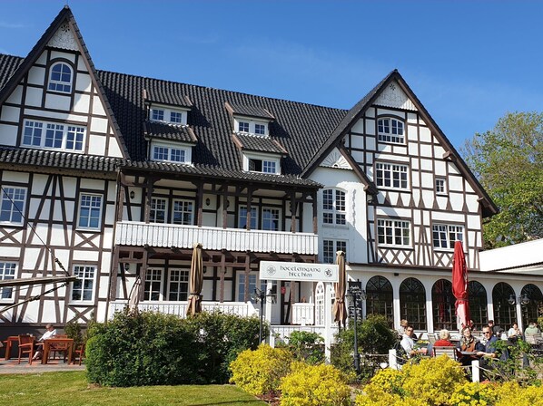 Un bâtiment traditionnel à colombages, doté d’un balcon et d’un espace extérieur aménagé pour s’asseoir.