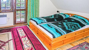 A room with a wooden bed, a window with curtains, and a radiator.