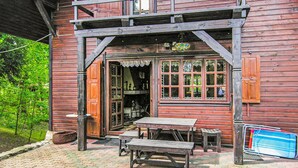 A rustic wooden building with a porch, a table, and benches.