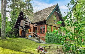Ein rustikales Holzhaus mit einem steilen Satteldach, einem Balkon und einer Treppe, die zum Obergeschoss führt.