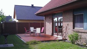 Una casa amb teulada de rajola, façana de maó i un pati amb mobiliari exterior.
