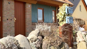 Una casa de façana de maó, porta de fusta i finestra amb persianes.