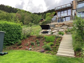 A residential property with a stone staircase, a covered outdoor seating area, and a view of a forested hillside.
