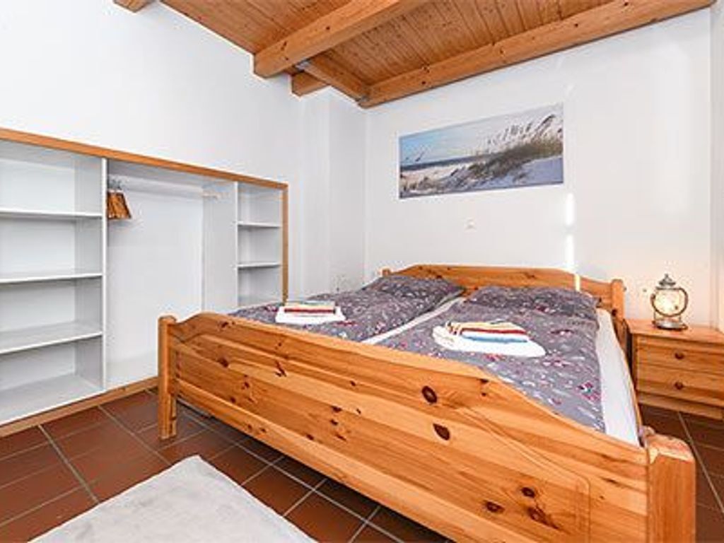 A bedroom with a wooden bed, a white wardrobe, and a painting on the wall.
