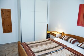A bedroom with a bed, a wooden headboard, a nightstand, a lamp, and a red abstract painting on the wall. - Holiday Apartment Gaude Stuv 1 - Holiday Apartments Gaude Stuv (Sellin)