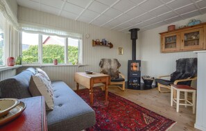 Relax in this serene space with a plush sofa, wood-burning stove, and a view of the surrounding greenery.