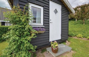 Guests can enjoy an entrance and a cozy porch area with a bench and a potted plant.