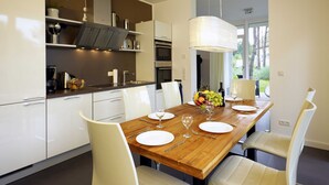 Un'area pranzo moderna con un tavolo di legno apparecchiato per quattro persone, sedie bianche e una grande lampada a sospensione.