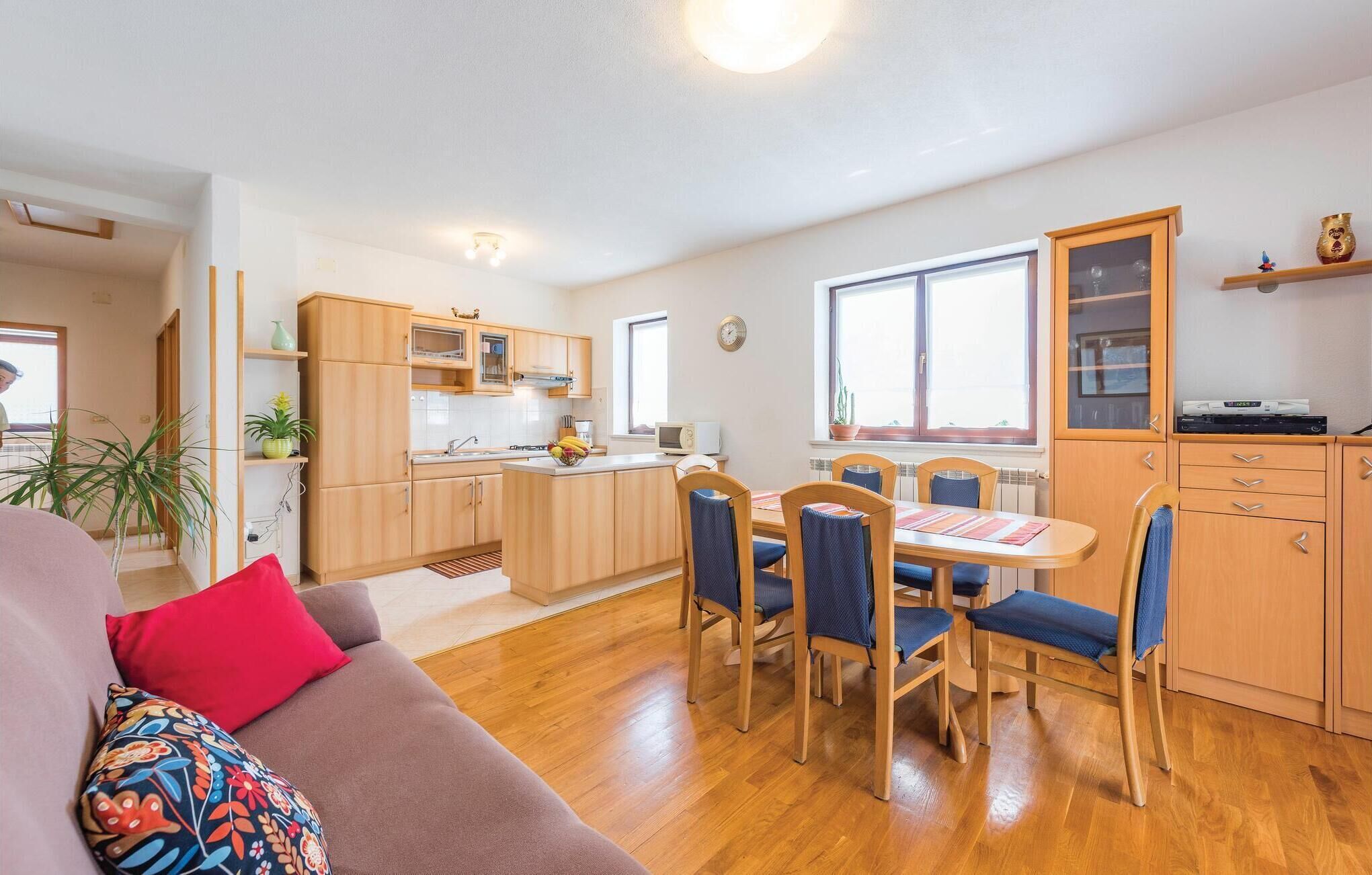 A compact living space with a kitchenette, dining area, and a sofa with colorful cushions.