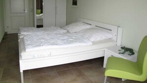 A bedroom with a bed, a green chair, and a wardrobe. - (257) 3-room apartment - apartment complex holiday dreams (Kühlungsborn)