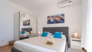 A modern bedroom with a large bed, two bedside tables, a mirror, and a painting of boats. - Cozy apartment in Zaton Mali (Zaton Mali)