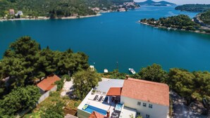 A coastal view with a clear blue sea, a small island with boats, and a building with a swimming pool. - Cozy apartment in Zaton Mali (Zaton Mali)