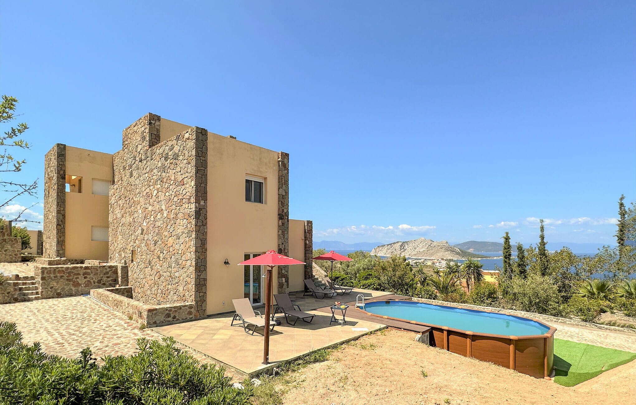 A villa with a stone facade, a swimming pool, and a view of the sea.