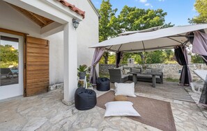 Eine Terrasse im Freien mit überdachter Sitzgruppe, Steinböden und einer Steinmauer.
