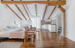 Ein Schlafzimmer mit Holzboden, einem Bett, einem Schreibtisch und einer Küchenzeile.