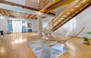 A spacious loft with exposed wooden beams, a large staircase, a hammock, and a geometric rug. - Stunning home in Lozovac (Lozovac)