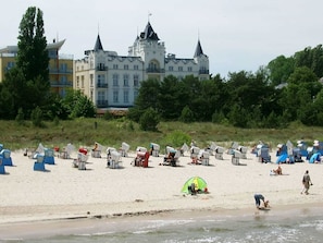 A beach with beach chairs and tents, a castle in the background, and a person walking on the sand. - Apartment "Wren" - Apartment "wren" (Zinnowitz)