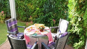 Une table ronde recouverte d’une nappe à carreaux, entourée de quatre chaises dotées de coussins à carreaux.