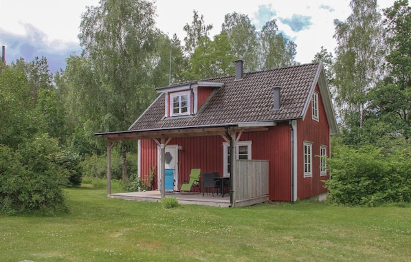 A red wooden house with a porch, a chimney, and a small deck area with outdoor furniture. - 2 bedroom awesome home in Holmsjö (Holmsjö)