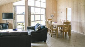 Un salon confortable avec un canapé, un téléviseur et un coin repas comprenant une table et des chaises.