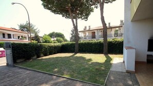 A courtyard with a paved area, a tree, and a building with a balcony. - Holiday home with garden, terrace and barbecue facilities (Lido delle Nazioni)