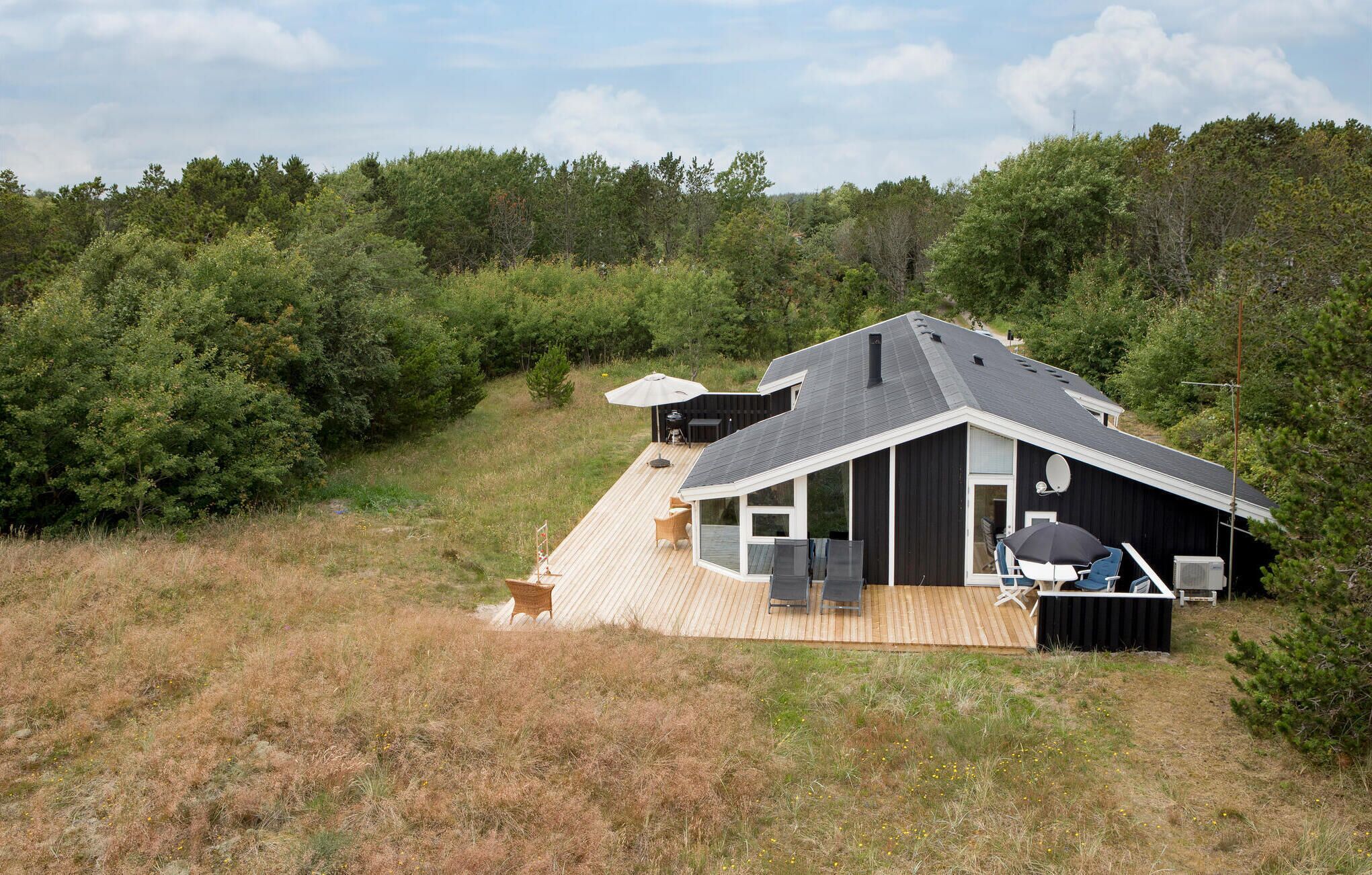 A modern house with a deck, large windows, and outdoor seating.