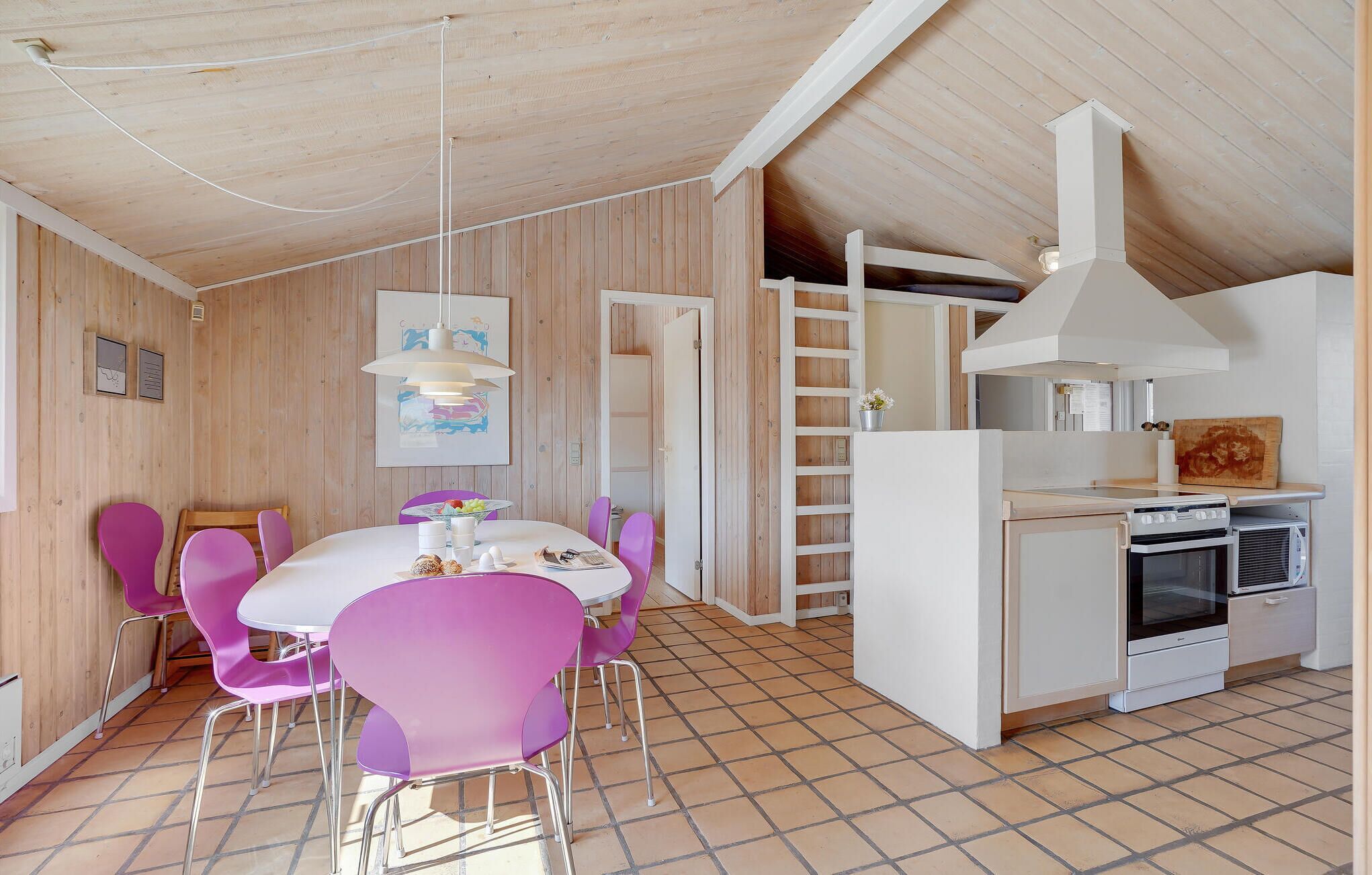 A dining area with a white table and purple chairs, a white stove, and a wooden ceiling.
