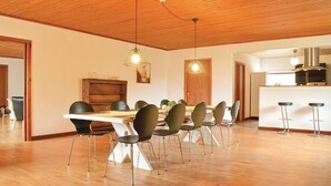 Ein moderner Essbereich mit Holztisch und -stühlen, Pendelleuchten und einer Küche im Hintergrund.