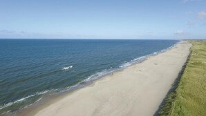 Ein Strand mit freiem Blick auf den Ozean und einer Rasenfläche am Ufer.