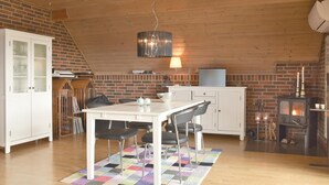 Una cocina acogedora con comedor, pared de ladrillo, techo de madera y chimenea.