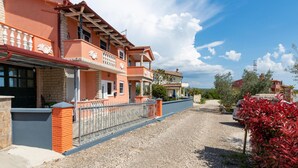A residential building with a balcony, a gravel driveway, and a red flowering plant. - Nice apartment in Betiga with WiFi (Betiga)