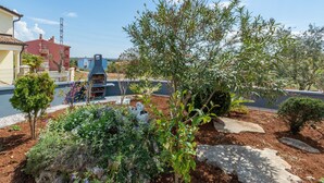 A garden with a barbecue area, various plants, and a stone wall. - Nice apartment in Betiga with WiFi (Betiga)
