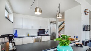 Een moderne keuken met witte kasten, een zwart aanrecht, een roestvrijstalen koelkast en een koffiezetapparaat.